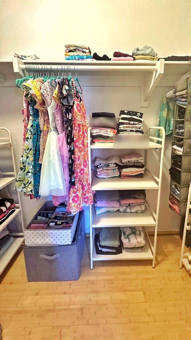 The same closet after: dresses hung on matching hangers, folded stacks on shelves, clear floor