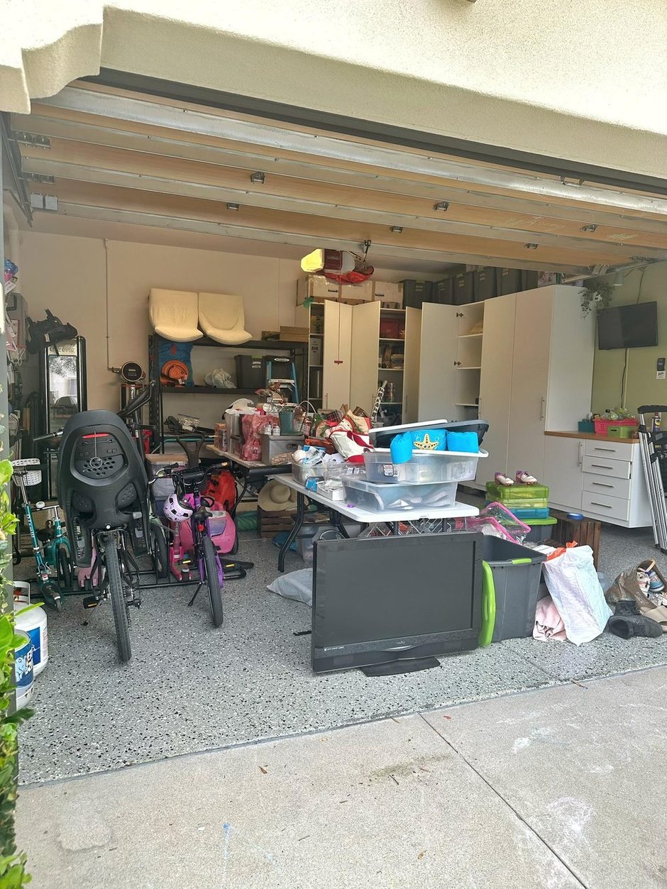 The garage before: folding tables piled with bins and boxes, a TV on the floor, no room to park